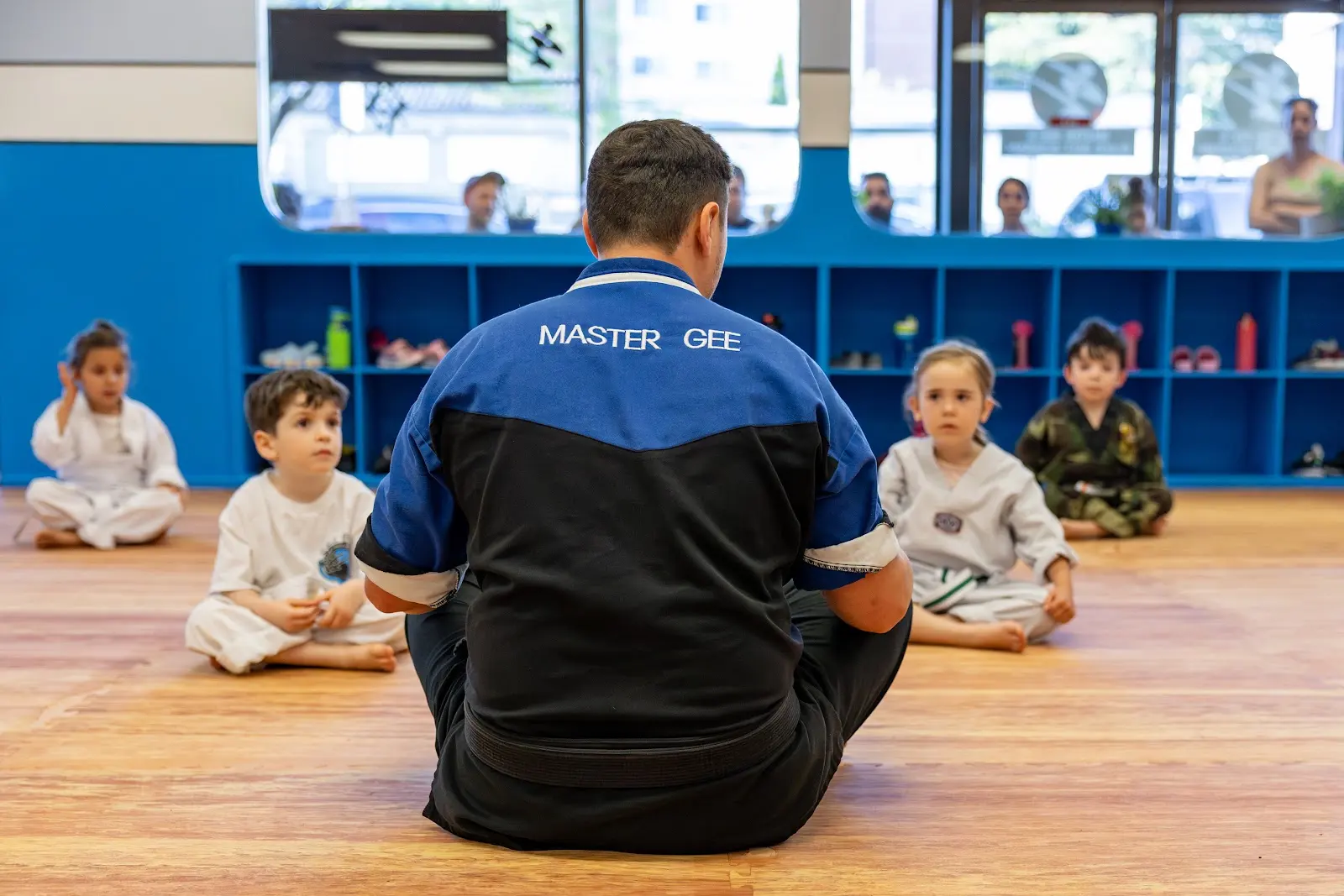 Instructor sitting with Tigers students on the mat